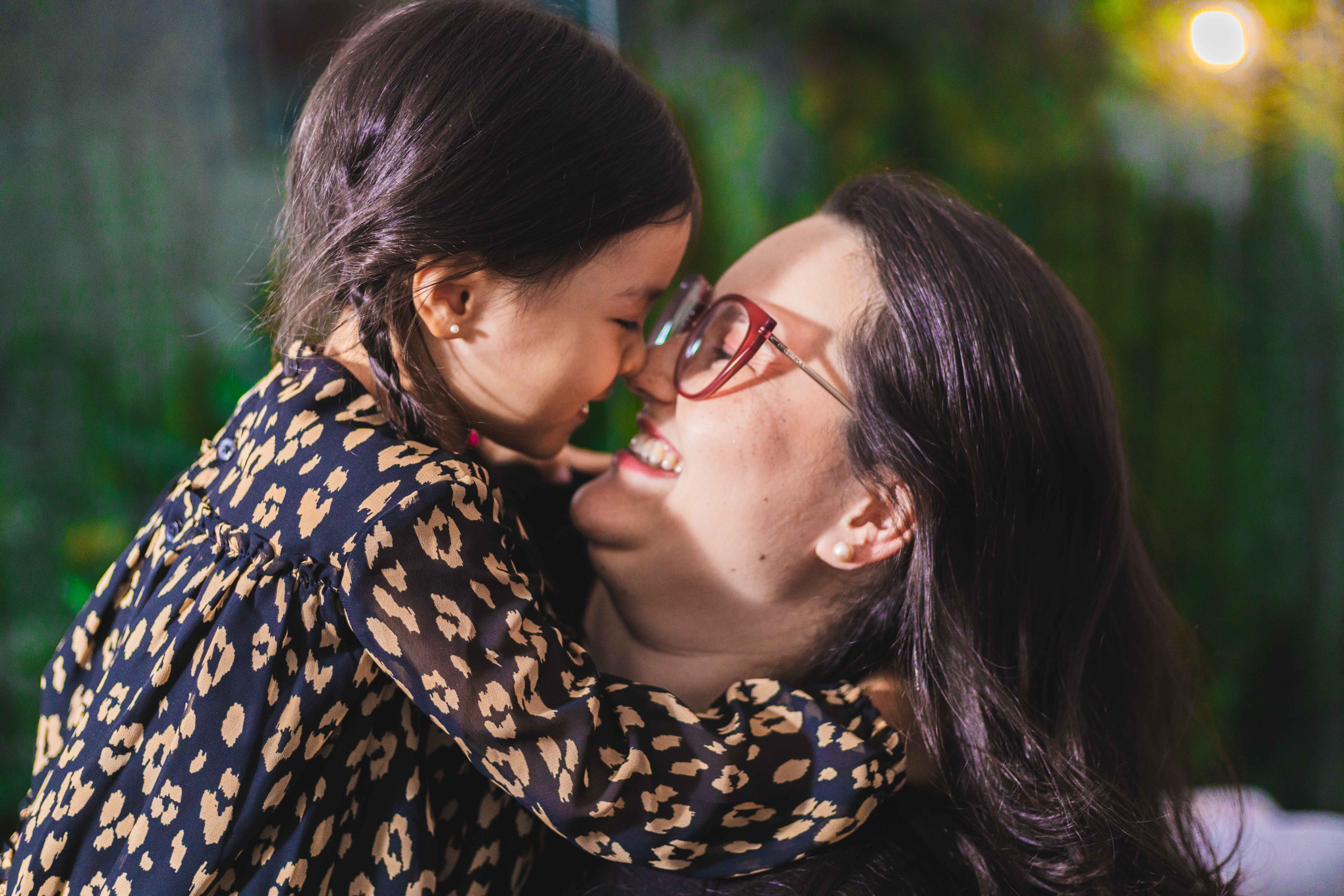 Mãe e filha sorrindo juntas, encostando os narizes